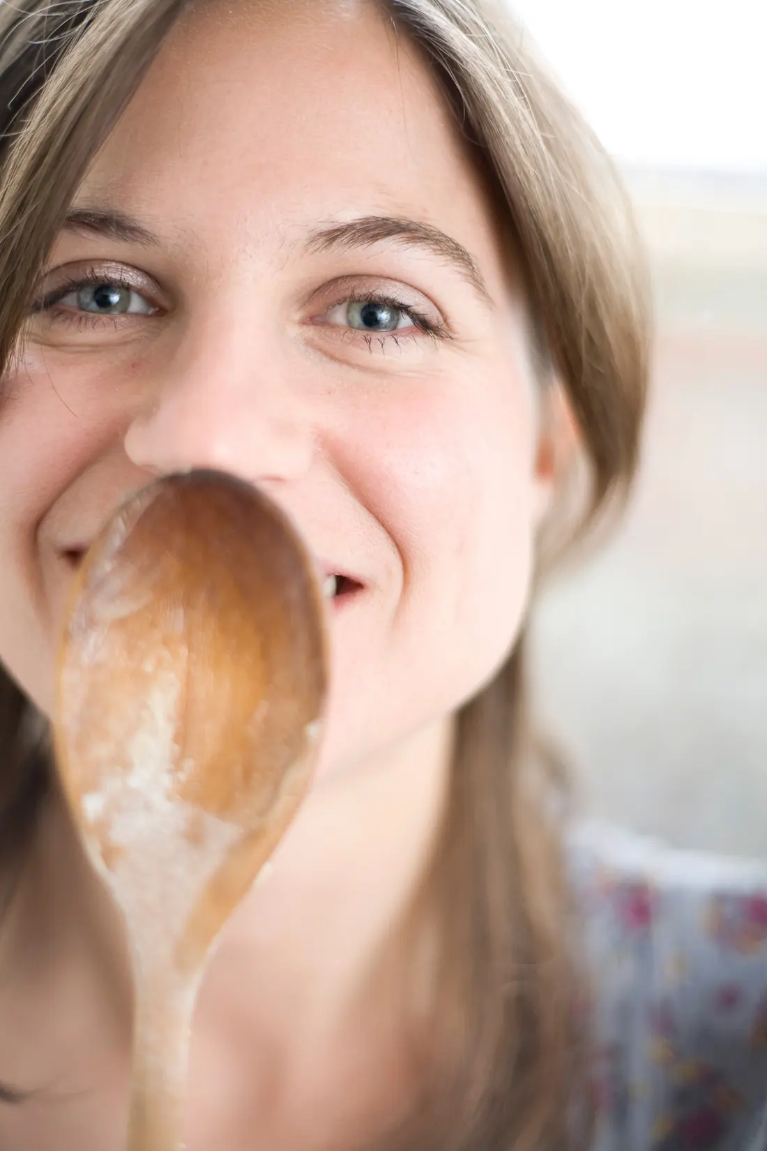 Elle, the head cook, smiling behind a wooden spoon